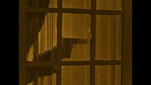 Still from the film Secrets of the Night - gun behind a curtain